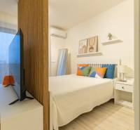 1 szobás lakás ággyal, televízióval és dekoratív párnákkal. Fa dekoros padló.