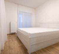 Hálószoba egy kétszobás lakásban, ággyal és fa dekorációjú padlóval.