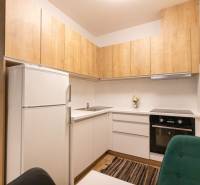 Konyha egy kétszobás lakásban fa dekorációval és fehér szekrényekkel.