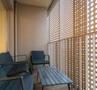 Erkély fa dekorációval, ülőgarnitúrával és perforált fallal egy kétszobás lakásban.