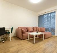 Nappali egy kétszobás lakásban kanapéval, asztallal és fa dekorációjú padlóval.