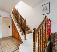 Családi ház belső tere lépcsőházzal, élénkvörös szőnyeggel és egy festménnyel a falon.