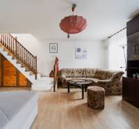 Nappali családi házban fa lépcsővel, kanapéval, szekrénnyel és fa mintázatú padlóval.