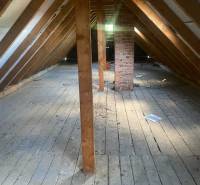 Padlás faházban fa gerendákkal és téglakéménnyel, fa dekorációjú padlóval.