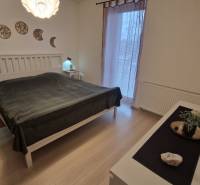 Hálószoba egy háromszobás lakásban, fa dekoros padlóval és faldekorációval.