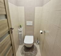 Háromszobás lakás WC-je fa mintázatú burkolattal és padlóval.