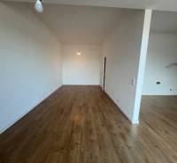 Szoba fa dekorációjú padlóval egy kétszobás lakásban, semleges falakkal.