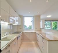 Konyha egy háromszobás lakásban nagy ablakkal, fehér szekrényekkel és fényes munkalappal.