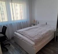 Hálószoba egy háromszobás lakásban ággyal, íróasztallal és fa dekorációjú padlóval.