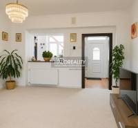 Nappali egy családi házban fehér falakkal, virágokkal és televízióval az asztalon.