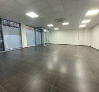 Kereskedelmi helyiségek sötét csempékkel, fehér falakkal és üveg kirakatokkal.