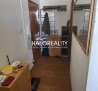 Előszoba egy egyszobás lakásban fa dekoros padlóval, tükörrel és tárolóhelyekkel.