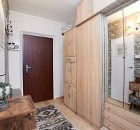 Előszoba egy kétszobás lakásban fa dekor padlóval, kőburkolattal és tükörrel ellátott szekrénnyel.