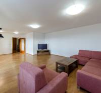 Nappali egy háromszobás lakásban kanapéval és fa dekorációjú padlóval.