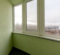 Üvegezett erkély egy 3 szobás lakásban, kilátással az épületekre és a természetre.