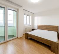 Hálószoba ággyal és fa dekorációjú padlóval egy háromszobás lakásban.