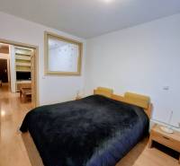 Hálószoba széles ággyal, éjjeliszekrényekkel és fa dekorációjú padlóval egy kétszobás lakásban.