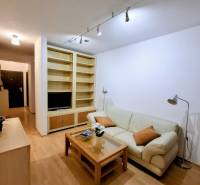 Nappali egy kétszobás lakásban krémszínű kanapéval és fa mintázatú padlóval.