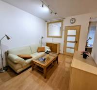 Nappali egy kétszobás lakásban kanapéval, lámpával és fa dekor padlóval.