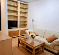 Nappali egy kétszobás lakásban bőrkanapéval és beépített polccal.