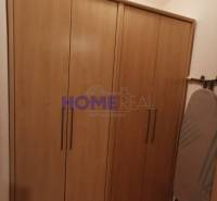 A kétszobás lakásban látható egy fa dekorációjú szekrény és egy vasalódeszka.