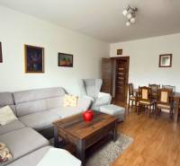 Nappali egy háromszobás lakásban sarokkanapéval és fa mintázatú padlóval.