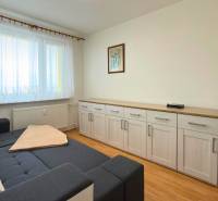 Szoba kanapéval, bútorokkal és fa dekorációjú padlóval egy háromszobás lakásban.