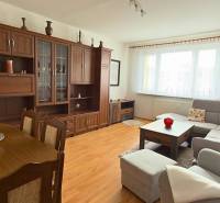 Nappali egy háromszobás lakásban, fa dekoros padlóval és nagy ülőgarnitúrával.