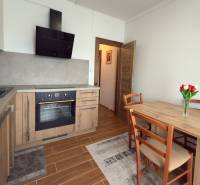 Konyha egy háromszobás lakásban fa dekorációval, étkezőasztallal és konyhabútorral.