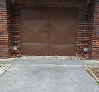 Garázs a mező előtt Trencsénben barna kapukkal és téglaburkolattal, 3 szobás lakás.