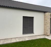 Családi ház külső része a Tomášov-i Fialkova utcában téglaburkolattal és gyepfelülettel.