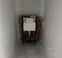 Függesztett WC telepítése egy családi ház fürdőszobájában. A falak és a padló nyersek.