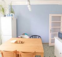 Étkező sarok egy háromszobás lakásban faasztallal és dizájnos padlóval.