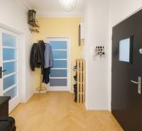 Folyosó egy 3 szobás lakásban, fa dekor padlóval, fogassal és ajtókkal.