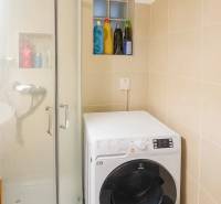 3 szobás lakás fürdőszobája zuhanyzóval és mosógéppel, bézs csempék.