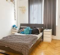 Hálószoba ággyal, éjjeliszekrényekkel és fa dekorációjú padlóval egy háromszobás lakásban.