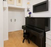 Egy 3 szobás lakás belseje antik fekete zongorával és fa dekorációjú padlóval.