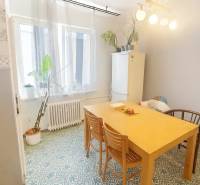 Étkező sarok egy háromszobás lakásban, fa asztallal és mintás padlóval.