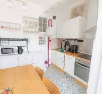 Konyha egy háromszobás lakásban étkezőasztallal, mintás padlóval és fehér szekrényekkel.