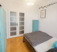 Hálószoba egy háromszobás lakásban, fa mintázatú padlóval és világos ajtókkal.