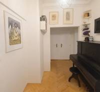 Folyosó zongorával és fa dekorációjú padlóval egy háromszobás lakásban.