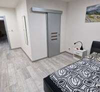 Hálószoba családi házban, fa mintázatú padlóval és tolóajtókkal.