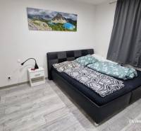 Hálószoba családi házban ággyal, éjjeliszekrénnyel és fa dekoros padlóval.