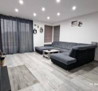 Nappali családi házban kanapéval, asztallal és fa dekorációjú padlóval.