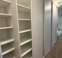 Beépített szekrény egy egyszobás lakásban tolóajtókkal és fa dekor padlóval.