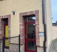 Sencen találhatóak irodák a téglából épült épületben, amelynek piros ajtaja van.