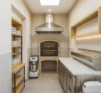 Professzionális konyha kemencével, munkaállomásokkal és tárolóhellyel kereskedelmi helyiségben.