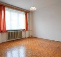 Szoba fa mintázatú padlóval, fehér falakkal és narancssárga függönyökkel egy családi házban.