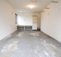 Családi ház garázsa betonpadlóval és fehér falakkal.