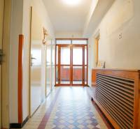 Folyosó egy családi házban csempével és fa radiátorfedéllel.